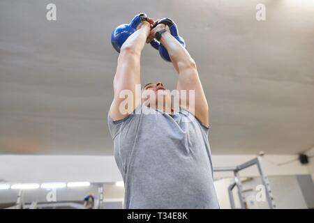 Starke Muskeln Athlet mann Training mit Kettlebells in der Turnhalle, Krafttraining. Stockfoto