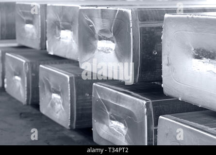 Schwere Aluminium-barren in einem Lager Gießerei gestapelt, Rohstoffe in einem heißen Mühle Foto in Schwarz und Weiß mit bläulichen Ton Stockfoto