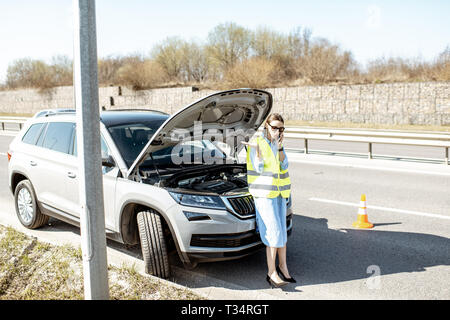 Peinlich, Frau Aufruf Pannenhilfe in der Nähe von Den kaputten Auto am Straßenrand der Autobahn Stockfoto