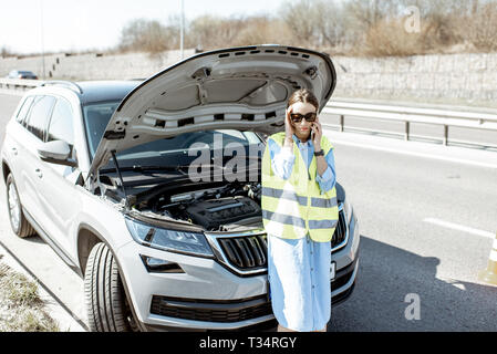 Peinlich, Frau Aufruf Pannenhilfe in der Nähe von Den kaputten Auto am Straßenrand der Autobahn Stockfoto