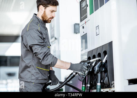 Tankstelle Arbeiter in Uniform, die Füllung Gewehr, tanken Auto an der Tankstelle Stockfoto