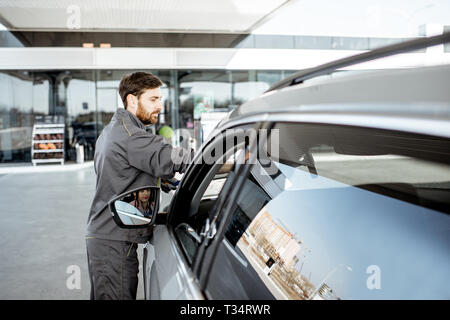 Tankstelle Arbeiter in Uniform waschen Auto Windschutzscheibe an der Station Stockfoto