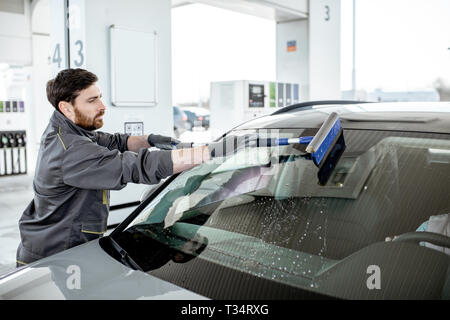 Tankstelle Arbeiter in Uniform waschen Auto Windschutzscheibe an der Station Stockfoto