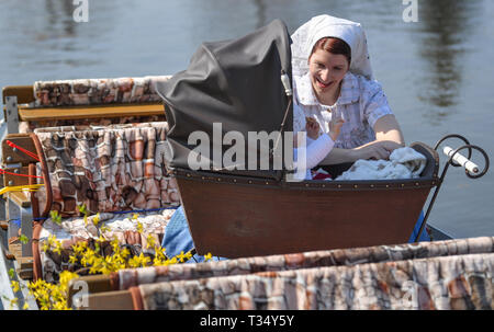 Brandenburg, Lübbenau, Deutschland. 6. April 2019. In sorbischer Outfit Anja Harms sitzt in einem Spreewald Kahn neben einem historischen Kinderwagen von 1900, in dem Ihre 10 Monate alte Tochter sitzt. Am gleichen Tag die neue Saison feierlich im Spreewaldhafen Lübbenau geöffnet. Über 1000 Kilometer Fluss laufen durch den Spreewald im Südosten des Landes Brandenburg. Foto: Patrick Pleul/dpa-Zentralbild/dpa Quelle: dpa Picture alliance/Alamy leben Nachrichten Stockfoto