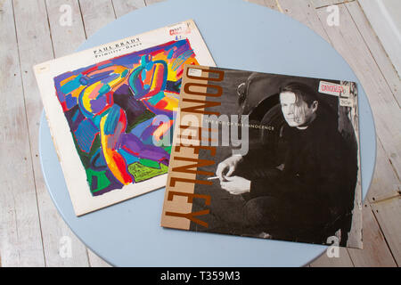 LP-Cover für Paul Bradys Album Primitive Dance aus dem Jahr 1987 und Don Henleys Album End of the Innocence aus dem Jahr 1989 auf einem runden, blassblauen Tisch Stockfoto