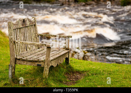 Holzbank vor der Stromschnellen auf einer gehenden Zug am Cassley fällt, Invercassley, Schottland. Stockfoto