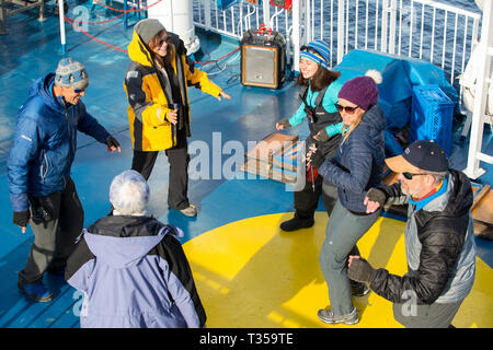 Passagiere und Crew tanzen auf dem Deck der Antarktis Kreuzfahrt Schiff zu feiern das Erreichen der Polarkreis in der Nähe von Crystal Sound, Antarktis. Stockfoto