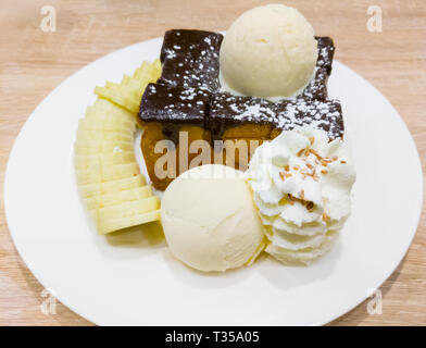 Honig Toast und Vanille Eis mit Schlagsahne und Banane Slice auf der hölzernen Tisch in den Nachtisch Cafe. Stockfoto