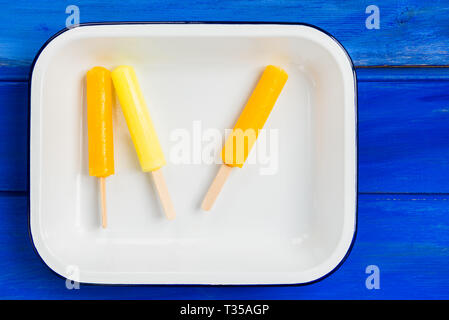 Ice Orange und Zitrone Eis am Stiel in das Fach auf blauem Hintergrund Stockfoto
