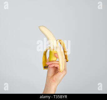 Geschälte frische Banane in weiblicher Hand auf weißem Hintergrund Stockfoto