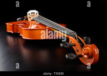 Schöne neue glänzende Violine auf einen dunklen Tisch. Musikalische string Instrument für Arbeit vorbereitet. Der dunkle Hintergrund. Stockfoto