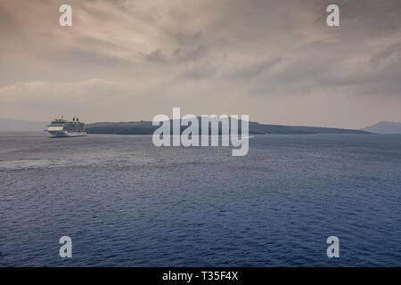 Panorama von Santorini an einem bewölkten Tag, mit Kreuzfahrtschiff Warten im Hafen, Kykladen, Griechenland Stockfoto