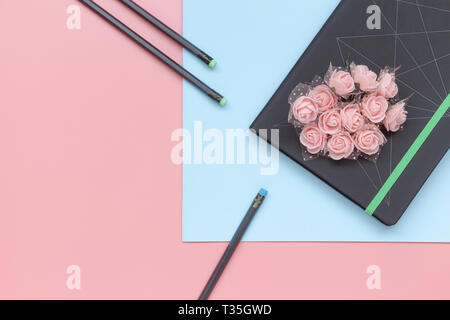 Ansicht von oben, Notebook mit Blumen und Bleistift auf Blau und Rosa Hintergrund. Flach Stil Stockfoto