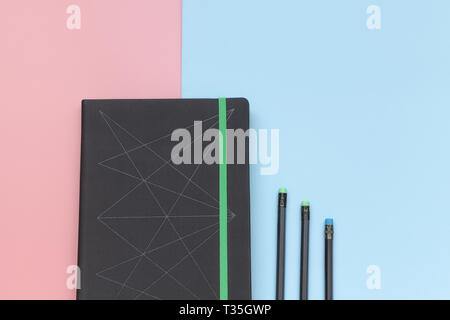 Ansicht von oben, Notizbuch und Bleistift auf Rosa und blauem Hintergrund. Close-up Stockfoto