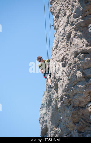 TAURANGA NEUSEELAND - 8. NOVEMBER 2012; junge unternehmungslustige Person rock bis Klettern Schere auf der Seite Mount Maunganui Stockfoto