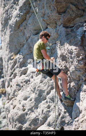 TAURANGA NEUSEELAND - 8. NOVEMBER 2012; junge unternehmungslustige Person rock bis Klettern Schere auf der Seite Mount Maunganui Stockfoto