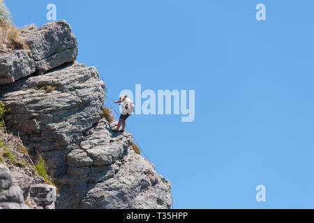 TAURANGA NEUSEELAND - 8. NOVEMBER 2012; junge unternehmungslustige Person rock bis Klettern Schere auf der Seite Mount Maunganui Stockfoto