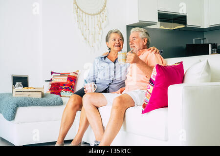 Gerne alte Senior kaukasischen Paar Mann und Frau zusammen zu Hause auf dem Sofa sitzen Trinken gesunde Kaffee für schöne Lifestyle - Begriff des wirklichen Lebens fo Stockfoto