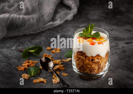 Cottage Käse Dessert mit Cornflakes in einem Glas Tumbler auf einem dunkelgrauen Hintergrund Stockfoto