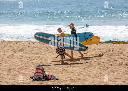 Zwei Männer zu Fuß auf dem Sand im Palm Beach ihre surfbretter Longboards, Sydney, Australien Stockfoto