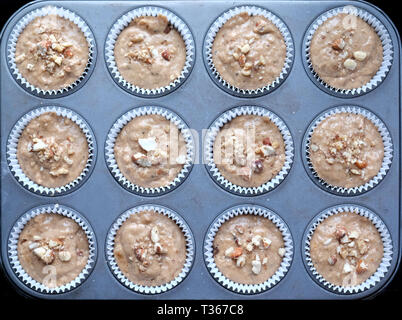 Ansicht von oben von 12 Backmischung cup cakes im Weißbuch Fällen auf einem Backblech in den Backofen zu gehen, die Kuchen und Backblech sehr Sym Stockfoto