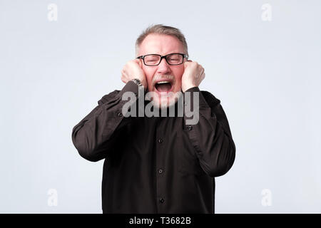 Ältere Menschen Ohren verstopfen mit Fingern. Studio schießen. Negative facial Emotion. Stockfoto