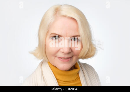 Schöne blonde ältere Frau lächelnd. Posititve facial Emotion. Nähe zu sehen. Studio shot Stockfoto
