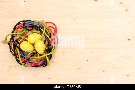 Ostereier und Nest von Internet Kabel auf Holzbrett Stockfoto