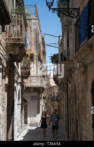 Street Scene von jungen Paar in reich verzierten Gasse über Dione in Ortigia, Syrakus, Sizilien Stockfoto