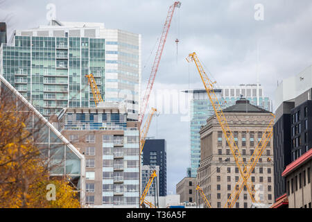 Krane und Gerät auf einer Baustelle eines Wolkenkratzers in der Innenstadt von Montreal, durch andere hohe Türme und Eigentumswohnungen sowie alte umgeben Stockfoto