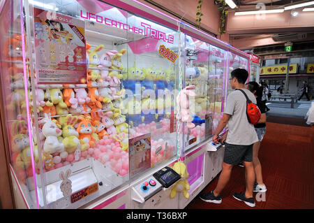 Tokyo, Japan - 5. Juli 2018: Leute, die vor ein typisch japanisches Spielzeug Kran Getränkeautomat in der Shinjuko Bezirk in Tokyo, Japan Stockfoto