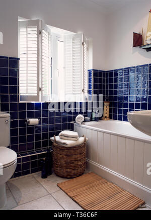 Weißen Fensterläden im Badezimmer mit blauen Kacheln Stockfoto