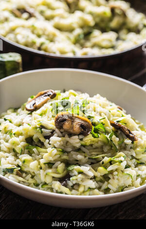 Italienische Risotto mit Zucchini Champignons und Parmesan in weiße Platte. Stockfoto