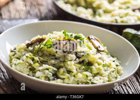 Italienische Risotto mit Zucchini Champignons und Parmesan in weiße Platte. Stockfoto