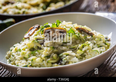 Italienische Risotto mit Zucchini Champignons und Parmesan in weiße Platte. Stockfoto