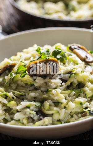 Italienische Risotto mit Zucchini Champignons und Parmesan in weiße Platte. Stockfoto