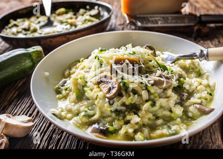 Italienische Risotto mit Zucchini Champignons und Parmesan in weiße Platte. Stockfoto