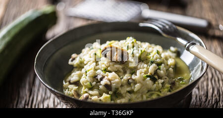 Italienische Risotto mit Zucchini Champignons und Parmesan in dunklen Platte. Stockfoto
