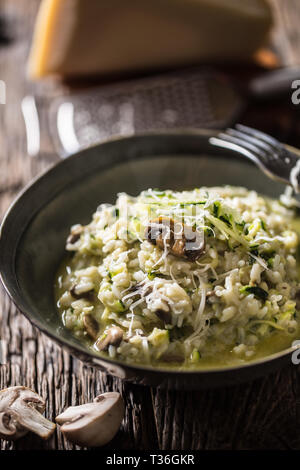 Italienische Risotto mit Zucchini Champignons und Parmesan in dunklen Platte. Stockfoto