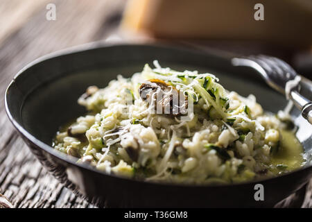 Italienische Risotto mit Zucchini Champignons und Parmesan in dunklen Platte. Stockfoto