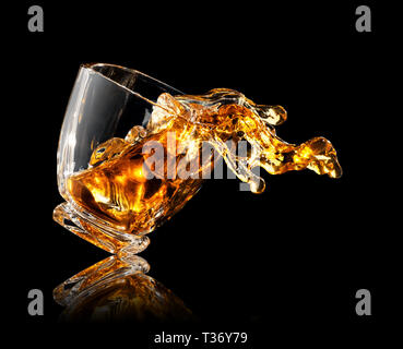 Splash Whisky mit Eiswürfel im Glas auf schwarzem Hintergrund Stockfoto