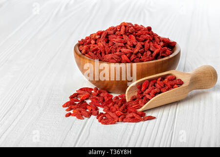 Goji Beeren in der Schüssel mit Schaufel auf weißen Tisch Stockfoto