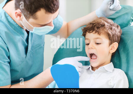 Junge Kind und Zahnarzt sind Kontrolle der Zähne im Spiegel. Stockfoto