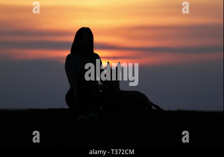 Silhouetten bei Sonnenuntergang, Mädchen und Hund vor dem Hintergrund der unglaublichen Sonnenuntergang, Belgische Schäferhund Malinois, Schmuse Stockfoto