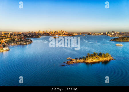 Blaue Wasserfläche von Sydney Harbour von Shark Island in Double Bay in Richtung entfernten Stadt CBD und die Harbour Bridge zwischen Ufer von Sydney. Stockfoto