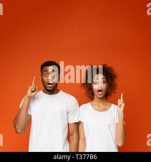 African-american Mann und Frau zeigen nach oben Schockiert Stockfoto