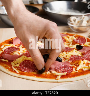 Pizza Art Mann hinzufügen Oliven pizza Stockfoto
