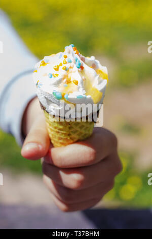 Hand hält Eis in der Waffel Kegel im Sommer unter der Sonne. Stockfoto