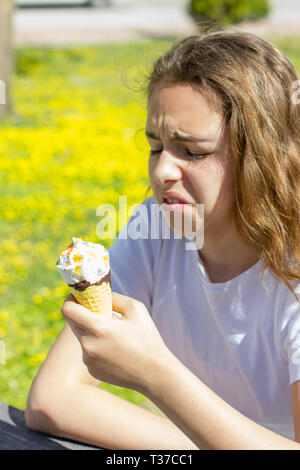 Unzufrieden unzufrieden jugendlich Mädchen geschmacklos Eis in der Waffel Kegel im Sommer isst. Selektiver Fokus Stockfoto