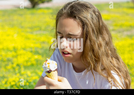 Unzufrieden unzufrieden jugendlich Mädchen geschmacklos Eis in der Waffel Kegel im Sommer isst. Selektiver Fokus Stockfoto